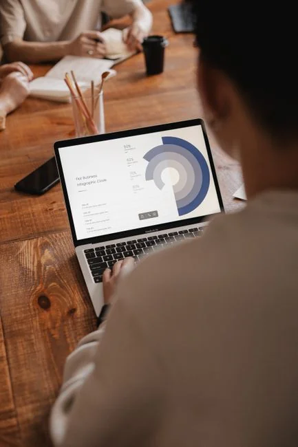 A modern workspace showing hands analyzing marketing data on a laptop and paper documents.